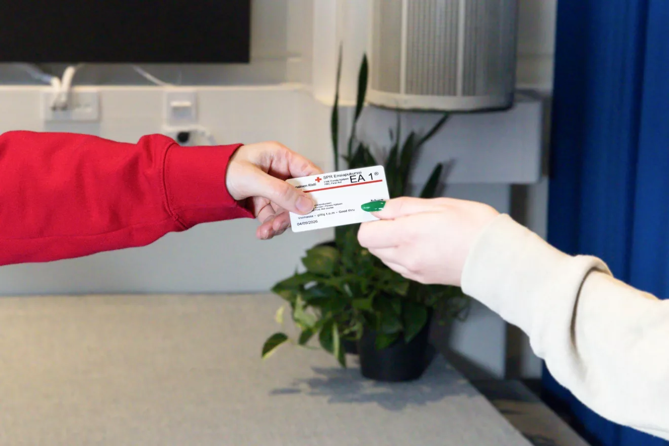 Trainer passing an FRC first aid certificate card to a course participant.