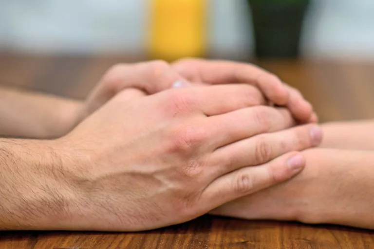 One person covers another's hands with theirs in show of support.