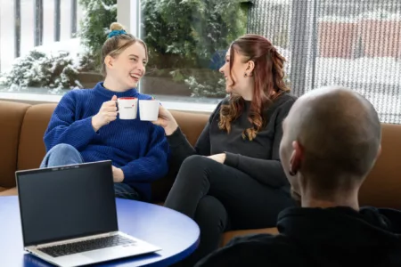 Two women clinking coffee cups in celebration of getting certified in first aid.