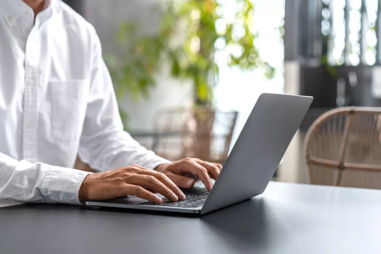 Man typing on the laptop keyboard.